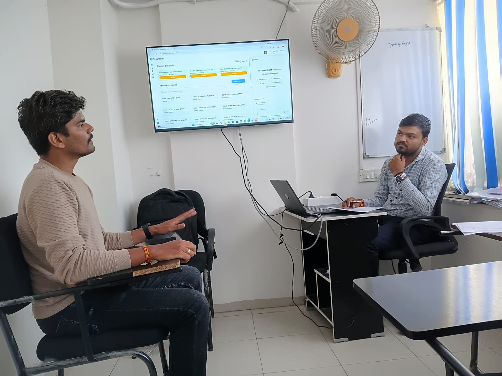 Two people in discussion beside a desk in the IT Accurate Nagpur classroom.